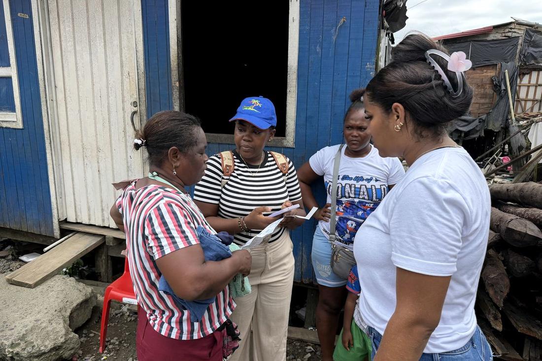 Encuestadora llenando la ficha digital con una familia frente a su vivienda